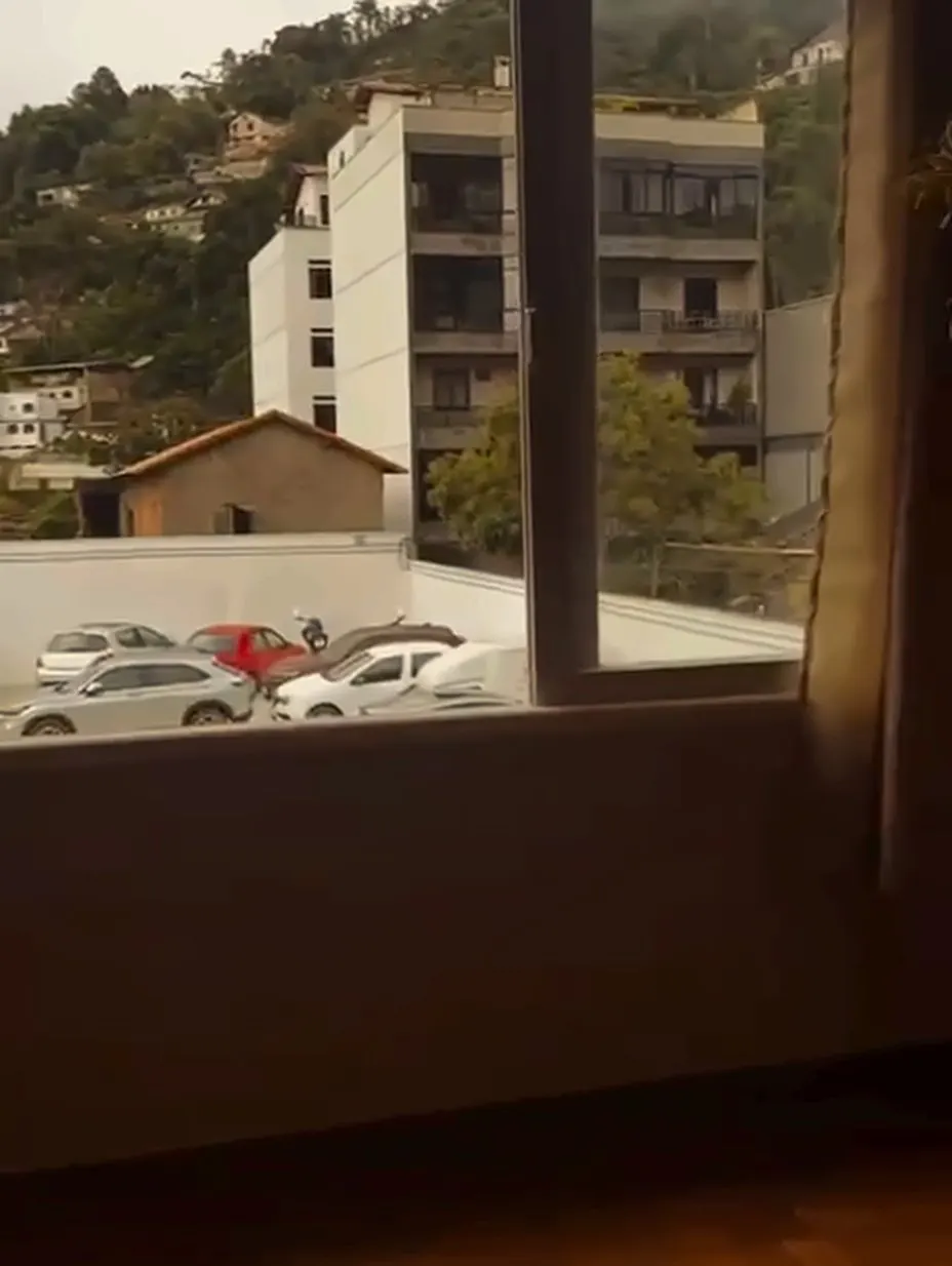 Vista da janela da sala coletiva para a cidade e as montanhas.